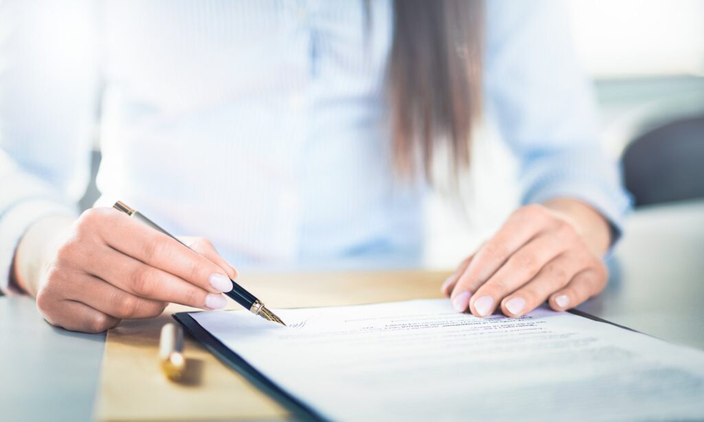 Woman holding a pen signing documents