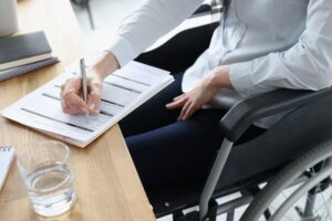 A person sitting in a wheelchair filling out paperwork